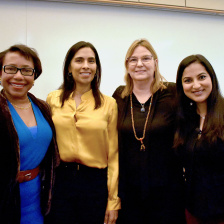 four women pose together with their arms around one another